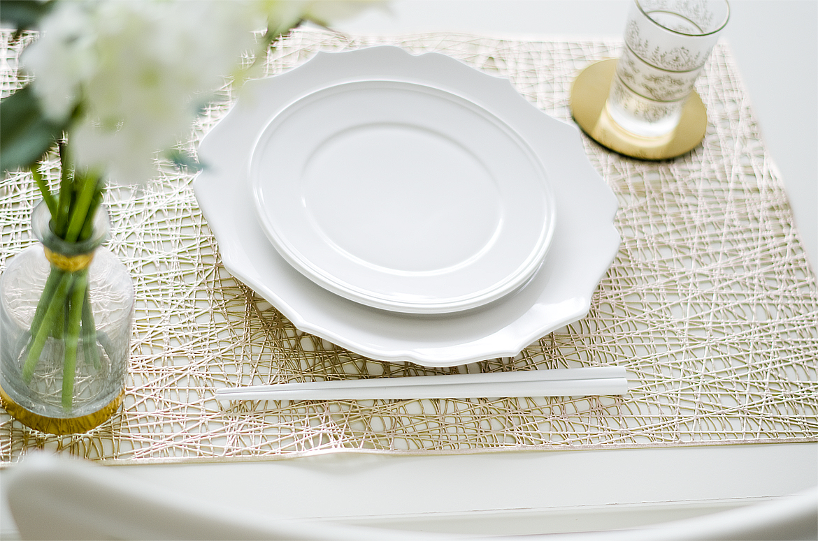 白いテーブルの上にゴールドのランチョンマットと白いお皿
